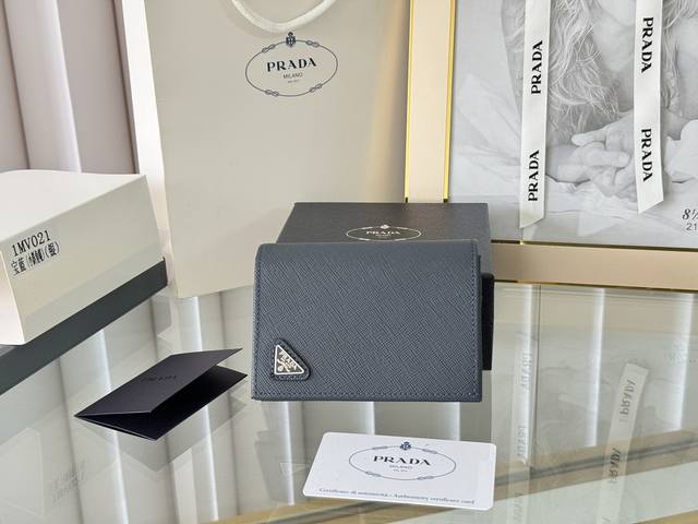 Prada 新款上线了 按扣式开合短夹， 男女通用，型号1Mv021， 颜色如图所示 一个钞票隔层，四个卡槽，两个内部口袋，另外还有一个拉链式口袋 十字纹牛皮制