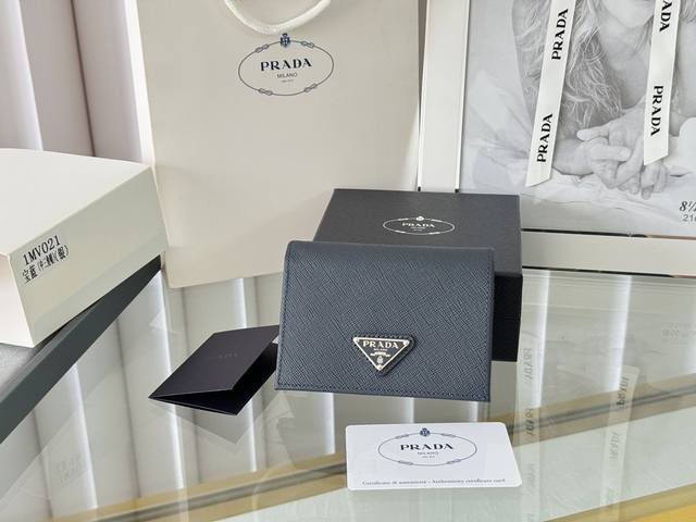 Prada 新款上线了 按扣式开合短夹， 男女通用，型号1Mv021， 颜色如图所示 一个钞票隔层，四个卡槽，两个内部口袋，另外还有一个拉链式口袋 十字纹牛皮制