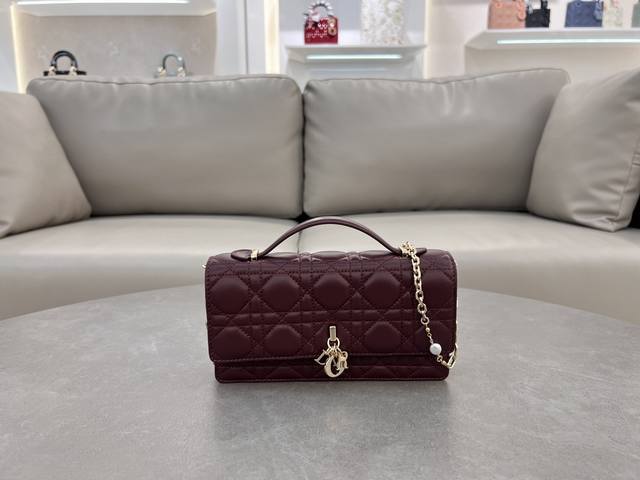 Lady Dior 珍珠手拿包 这款手拿包是本季新品，顶部搭配手柄，优雅实用，令 Lady Dior 系列更加丰富。采用酒红羊皮皮革精心制作，饰以藤格纹，翻盖设