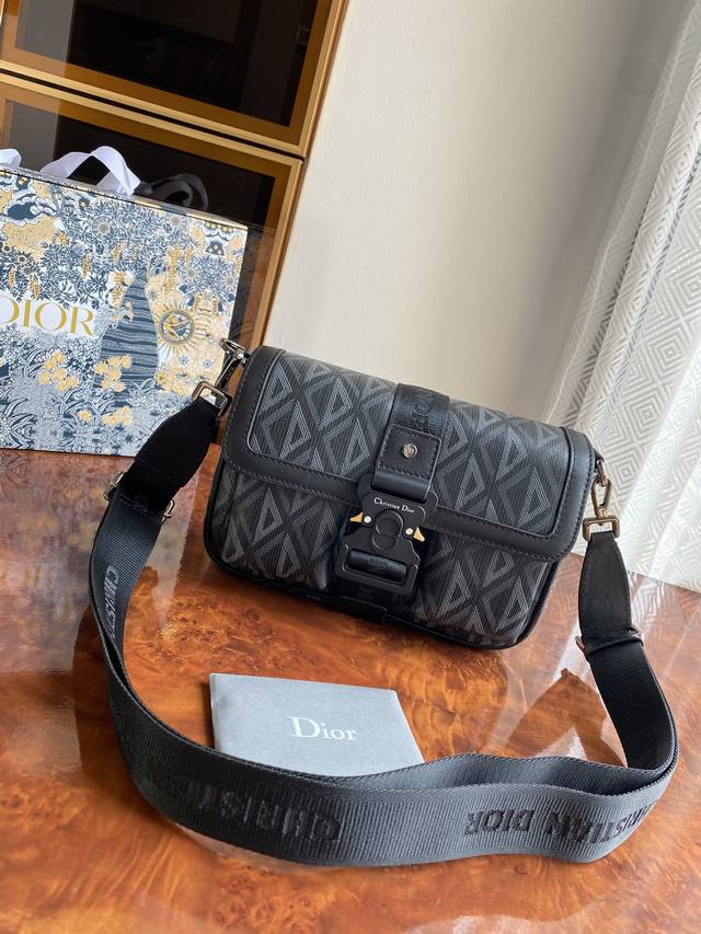 Dior Hit The Road 手袋搭配肩带，将现代风格与 Dior 的高订精神融为一体。采用海军黑色 Cd Diamond 图案帆布精心制作，翻盖搭配 C