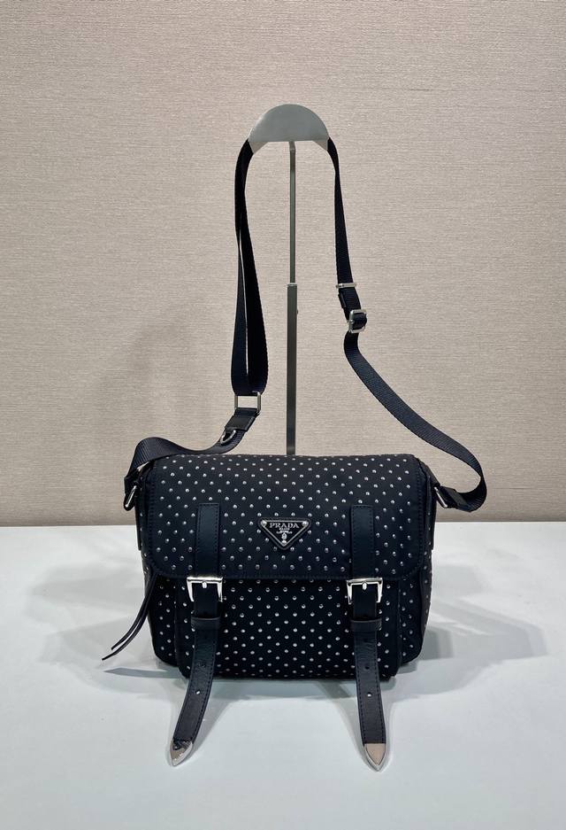 铆钉邮差包1Bd382新品 这款实用的单肩包由再生尼龙制成，造型轻巧，搭配可调式肩带与多个口袋，翻盖设计。迷你纯手工铆钉装饰更添摩登时尚。上身效果非常时尚独特，