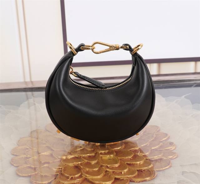 Nano迷你 少量出货 Graphy新月包,柔软的黑色皮革材质,于腋下背携时可看见复古金色金属fendi字样。拉链开合,设有布料衬里内隔层,配金色金属件。配有可 Nano迷你 少量出货 Graphy新月包,柔软的黑色皮革材质,于腋下背携时可看见复古金色金属fendi字样。拉链开合,设有布料衬里内隔层,配金色金属件。配有可