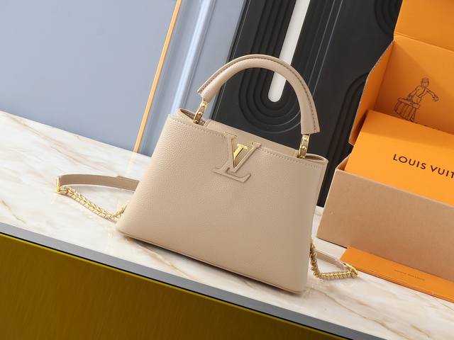 升级原版 M59709 本款 Capucines Bb 手袋以 Taurillon 皮革宣示摩登气场，其皮革编织链条可随心取下或调节，令肩背和斜挎自如切换。翻盖