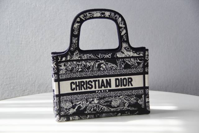 Dior Mini Book Tote 迷你款式，通体饰以蓝色刺绣 Reverse 茹伊印花，全新演绎标志性图案，突显反色效果。这款手袋充分体现了精湛的工艺，可