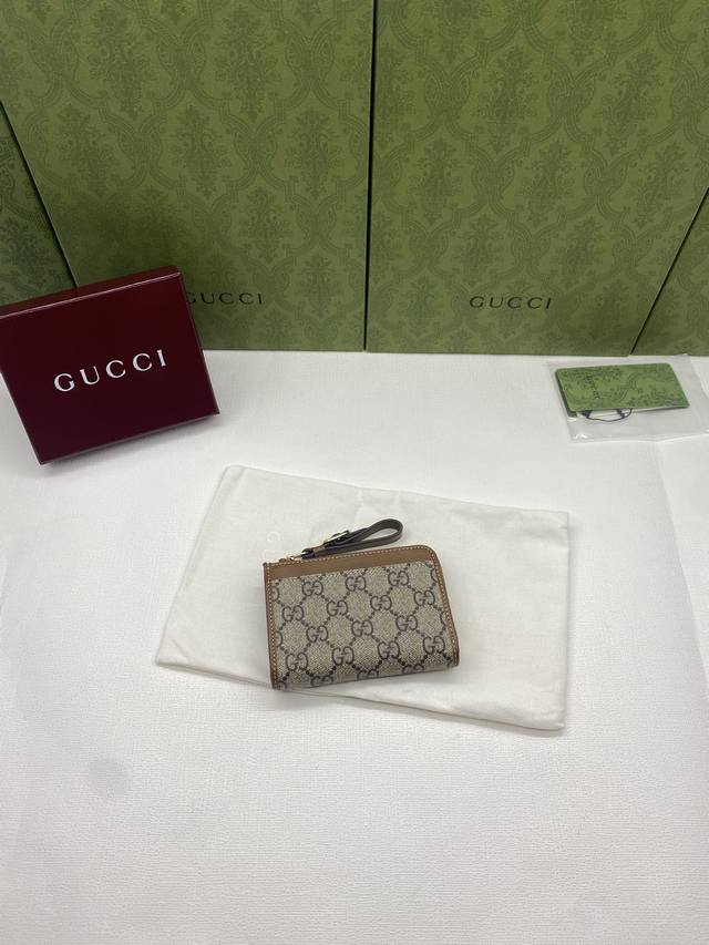 配红盒包装 新款 Gg Emblem系列饰包带卡片夹 Gg Emblem系列以创意设计和创新功能焕新诠释经典图案，匠心缔造未来数年的珍藏之选。这款米色和深棕色卡