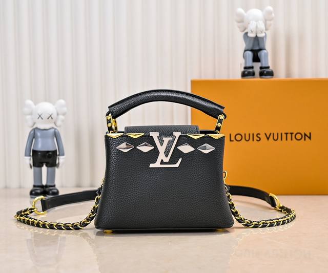 升级版 M12134黑色本款Capucines迷你手袋取材Taurillon牛皮革，以光泽熠熠的菱形金属元素塑造Malletage上缘，彰显当季新颖设计。翻盖提