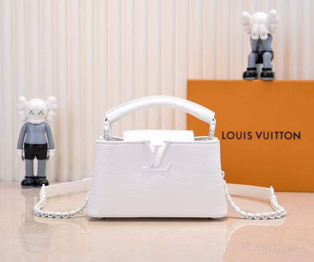 升级版 M23977白色鳄鱼纹本款Capucines小号手袋为哑光Taurillon牛皮革搭配金属件，令经典设计展露利落风范。翻盖提供外置或内收两式风尚，齐整内