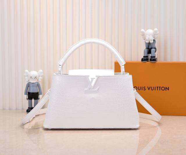 升级版 M23978白色鳄鱼纹本款Capucines大号手袋为哑光Taurillon牛皮革搭配金属件，令经典设计展露利落风范。翻盖提供外置或内收两式风尚，齐整内