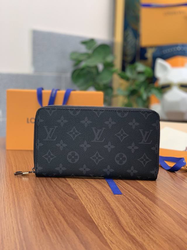 M60002 黑花！ 由全新标志性黑灰Monogram Eclipse帆布裁制而成，此款风格硬朗、极为实用的Zippy大号钱夹在容量上足可与小包袋相媲美。配有智