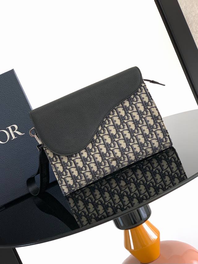 A5 三角手拿包是 Dior 的全新主打单品。采用米色和黑色 Oblique 印花面料等材质精心制作，搭配黑色粒面牛皮革马鞍廓形翻盖，宽敞的拉链隔层可收纳手机，