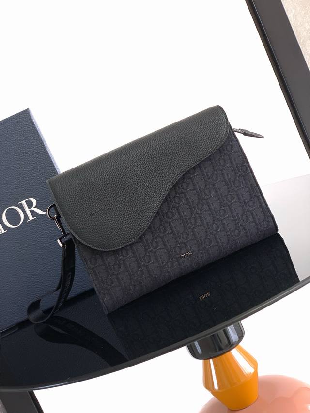A5 三角手拿包是 Dior 的全新主打单品。采用黑色 Oblique 印花面料等材质精心制作，搭配同色调粒面牛皮革马鞍廓形翻盖，宽敞的拉链隔层可收纳手机，另外