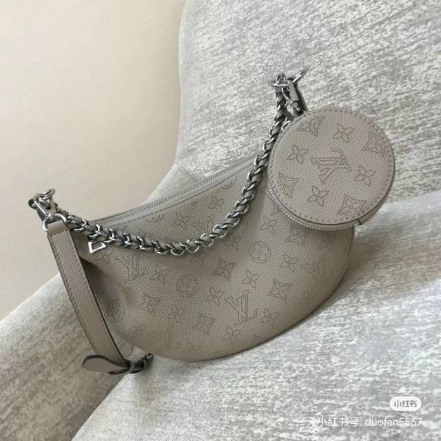 原厂小牛皮型号：M22819黑色 M22820 灰色 M22959蓝顶级原单 Baia 小号镂空月亮包，这款手袋取材柔软垂坠的镂花穿孔牛皮革，以舒适贴身的半月形