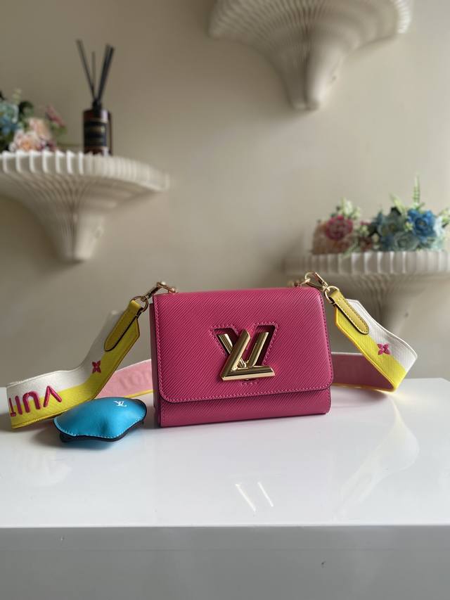 工厂价 Twist 小号手袋 M20693 玫红柠檬 本款 Twist 小号手袋迸发动感活力。灵动柠檬形状挂饰可从顶部开启，化身风琴零钱包。刺绣织物肩带拥有两式