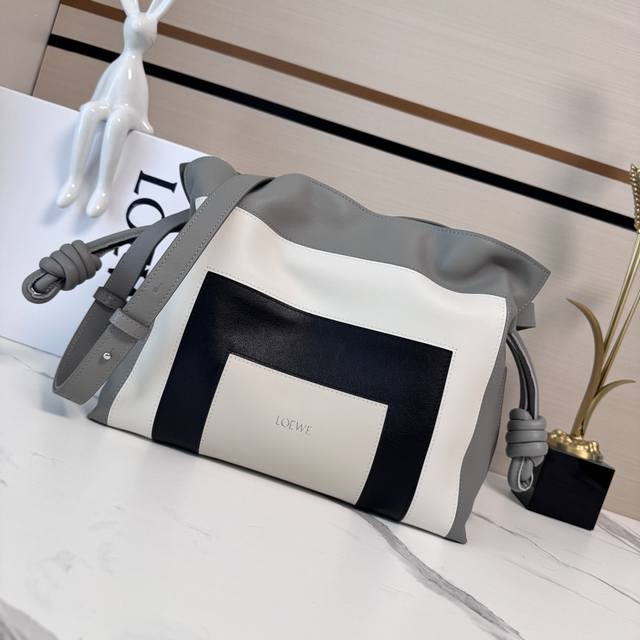 Lw 新版本 Flamenco 福袋以柔软材质制造就慵懒风格，拉绳设计饰有历史悠久绳结。此中号版本采用纳帕牛皮革制成此版本采用纳帕牛皮革制成，方形嵌花图案的灵感