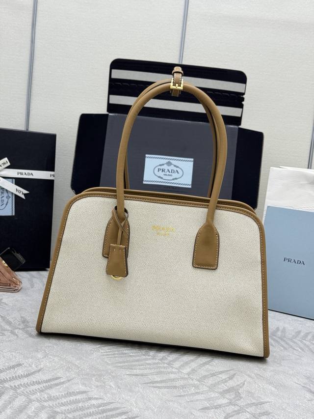 新款亚麻布托特包1Bg572 这款包袋结合牛皮与亚麻混纺面料的百搭风尚与轻盈质感，塑就Oversize廓形，巧妙演绎二元性。功能实用，设计精致，精湛细节彰显P家