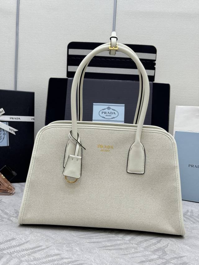 新款亚麻布托特包1Bg572 这款包袋结合牛皮与亚麻混纺面料的百搭风尚与轻盈质感，塑就Oversize廓形，巧妙演绎二元性。功能实用，设计精致，精湛细节彰显P家