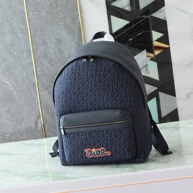 这款 Rider 2.0 拉链双肩背包来自Dior And Kaws 限定系列。采用海军蓝色粒面牛皮革等材质精心制作,正面大号拉链口袋饰以同色调 Oblique 这款 Rider 2.0 拉链双肩背包来自Dior And Kaws 限定系列。采用海军蓝色粒面牛皮革等材质精心制作,正面大号拉链口袋饰以同色调 Oblique